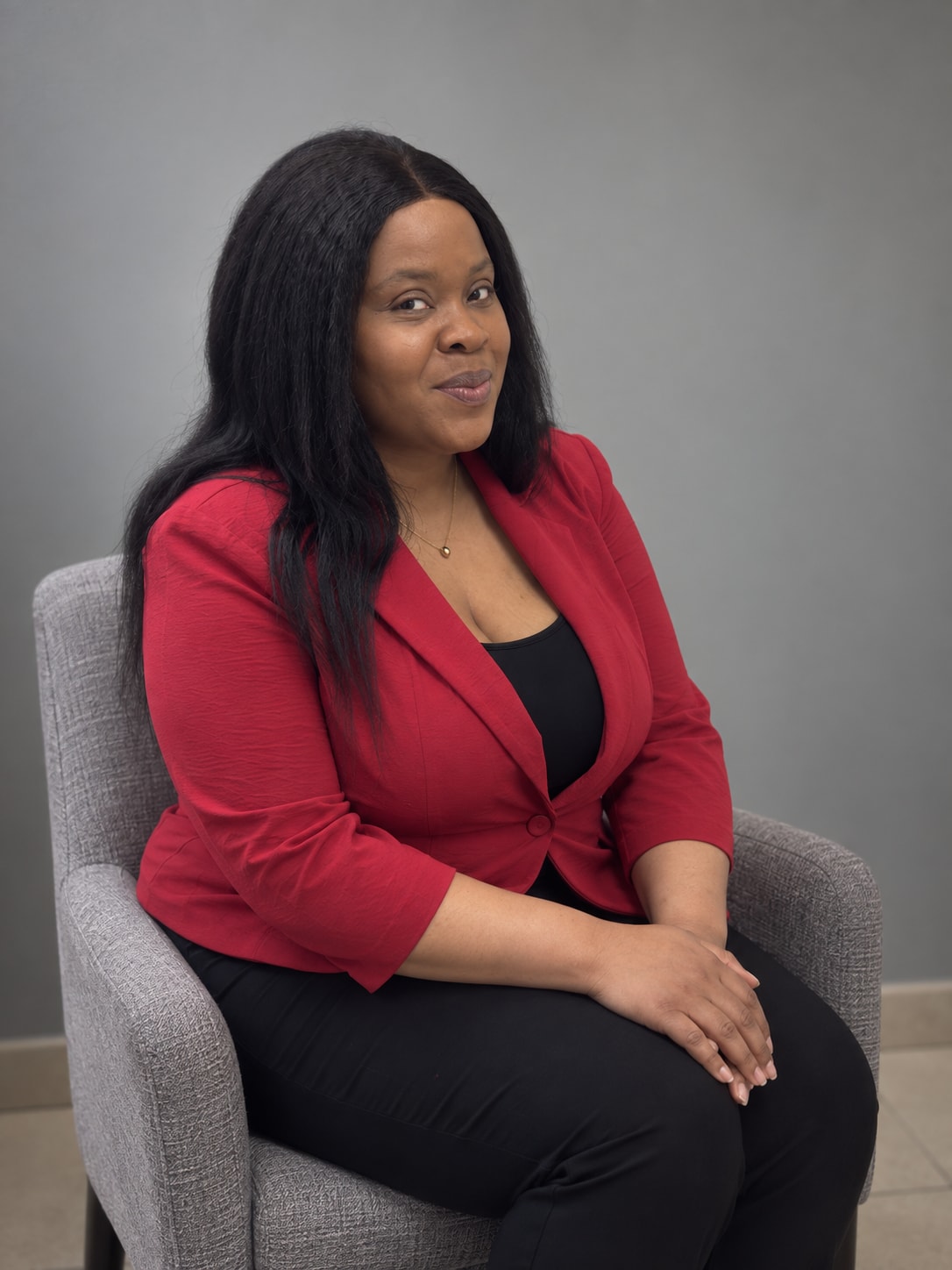 Natacha Alcindor seated in an armchair, hands folded, looking toward the camera